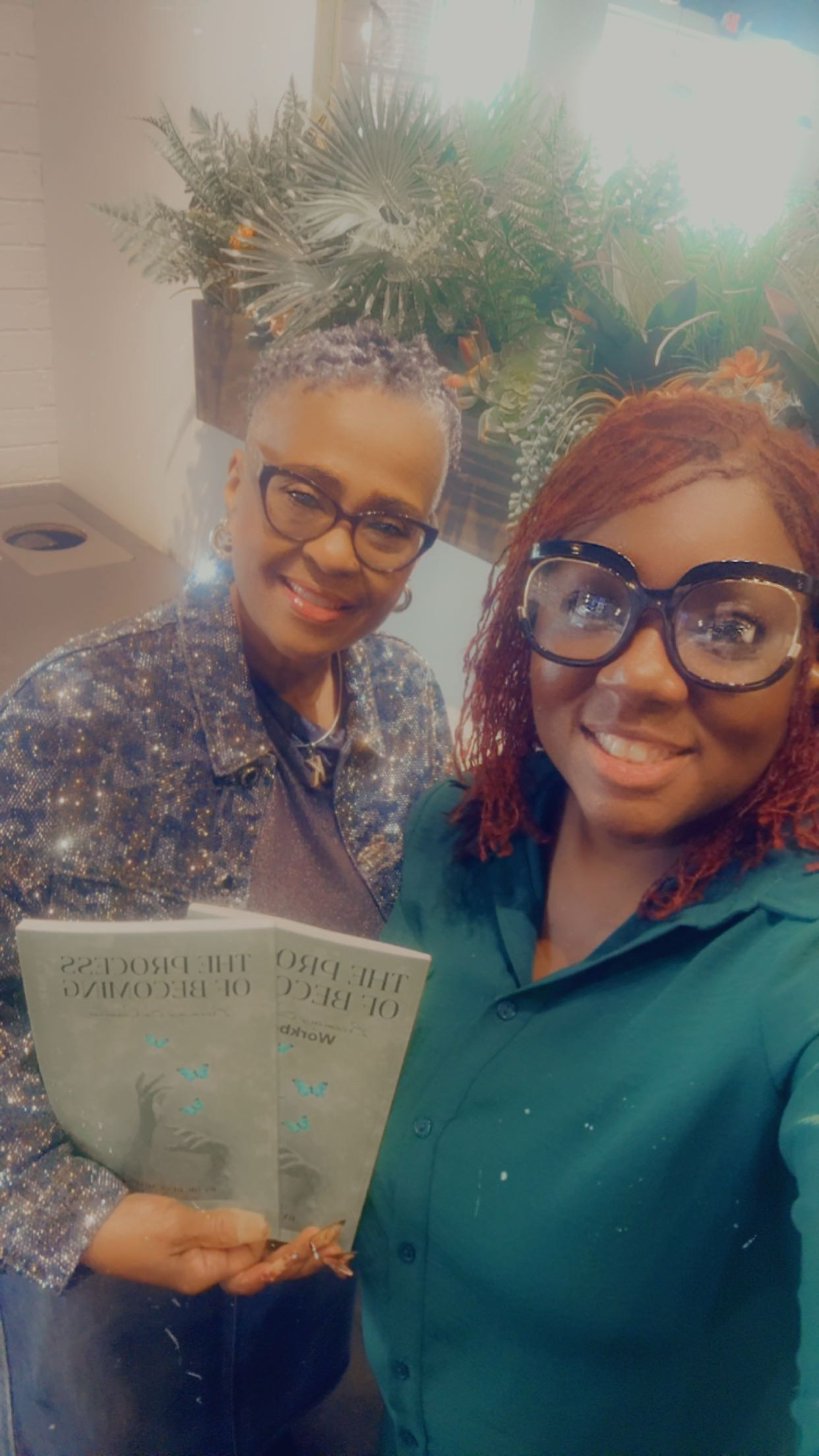 Two women taking selfie with The Process of Becoming book
