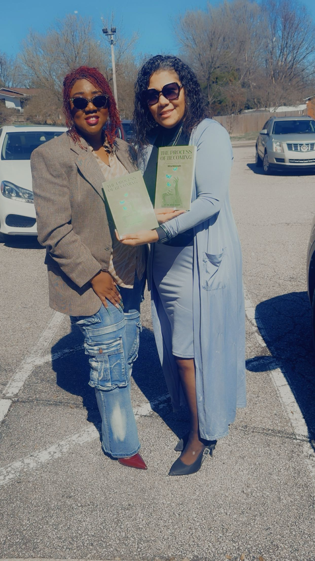 Two women outdoors holding books together