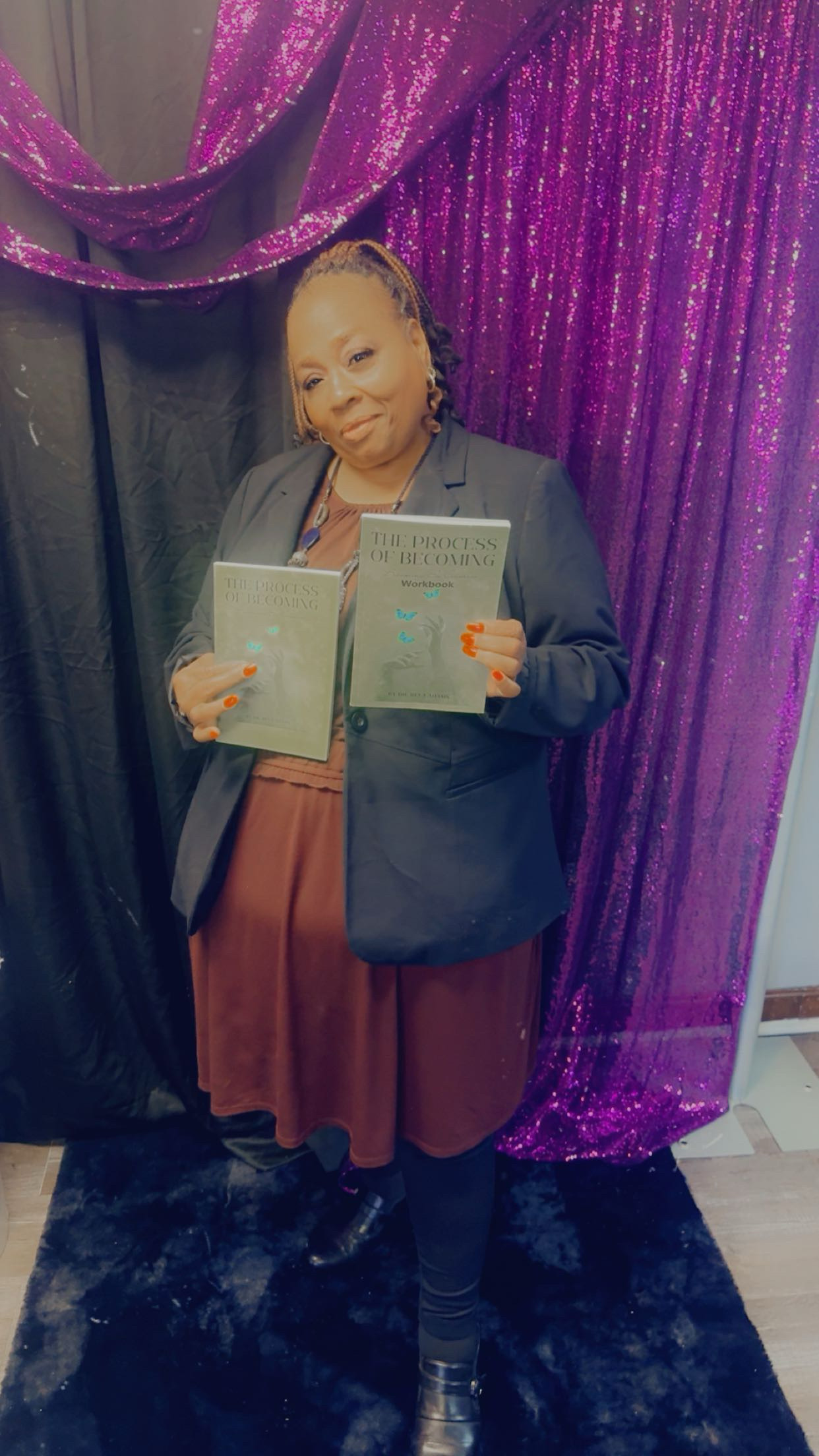 Woman in blazer holding books against purple backdrop